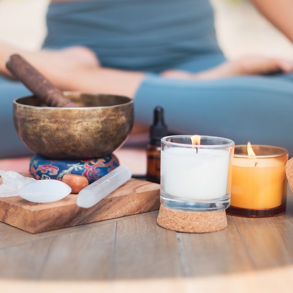 someone sitting in yoga lotus position with a sound bowl and candles